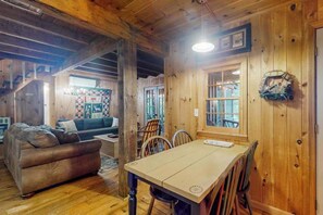 Ein Holzblockhaus-Interieur mit Esstisch, Stühlen, einer Couch und einer Treppe.