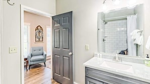 Une salle de bain avec un lavabo blanc, un grand miroir et un rideau de douche.