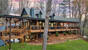 Eine Lodge mit einer Holzterrasse, mehreren Etagen und einem Steinfundament.