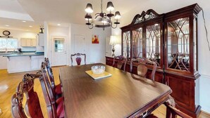 Uma sala de jantar com mesa de madeira, cadeiras e lustre.