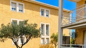 A building with a yellow exterior, a tree, and a garden with lavender plants. - BETWEEN THE HARBOR AND THE BEACH (Marseillan)