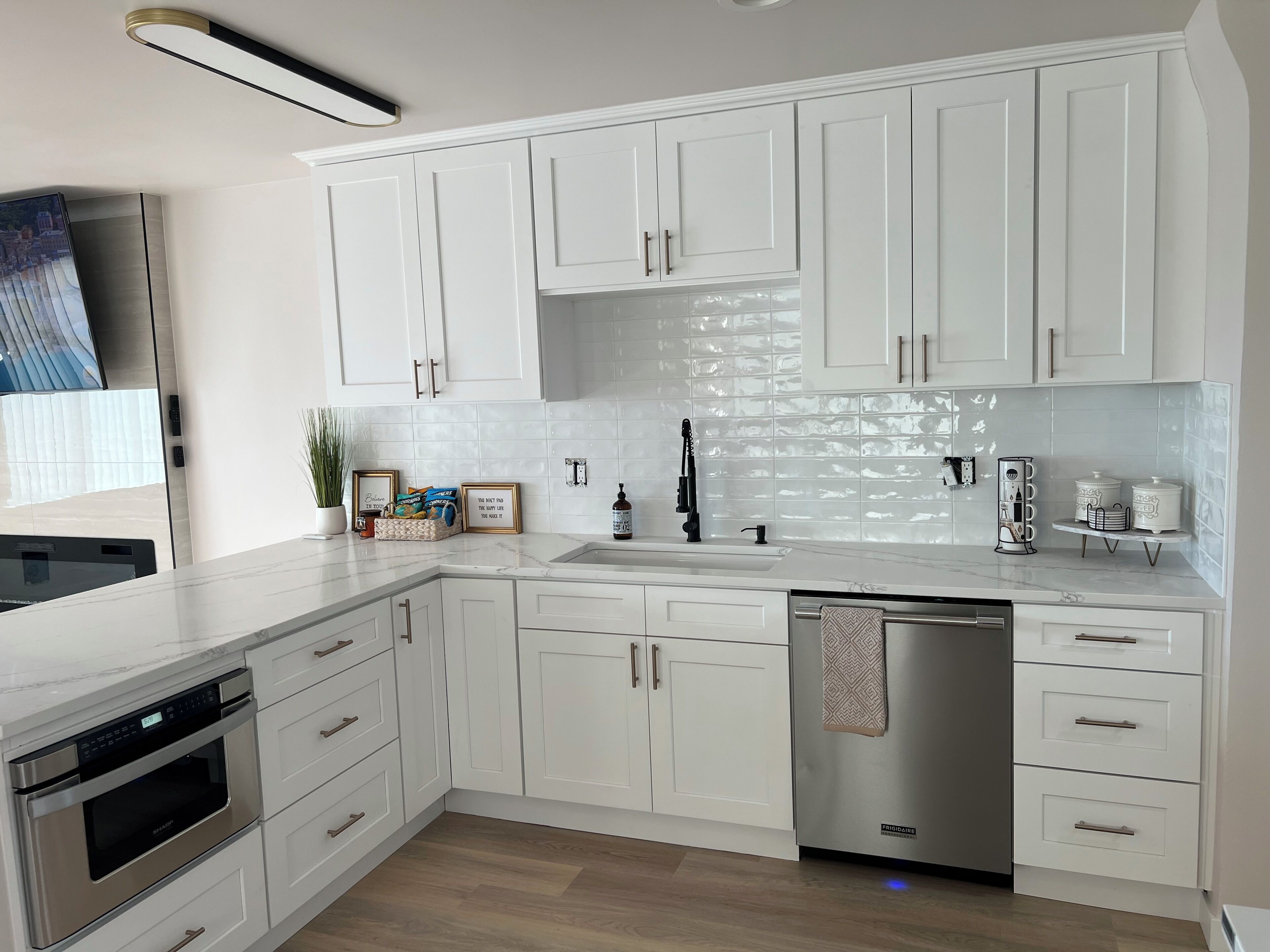 A modern kitchen with white cabinetry, stainless steel appliances, and a tiled backsplash.