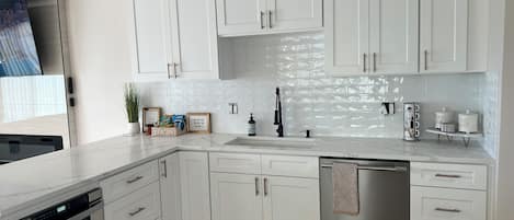 Una cocina moderna con armarios blancos, electrodomésticos de acero inoxidable y salpicadero de azulejos.