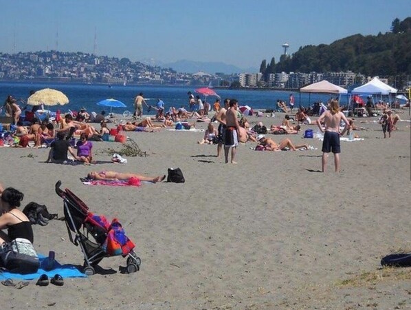 A beach with people sunbathing, umbrellas, and a stroller. - Tranquil 1-bedroom apartment with AC in Alki Beach Seattle (Seattle)