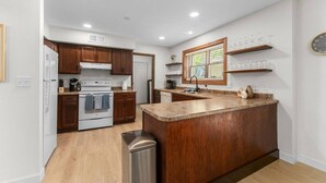 A modern kitchen with wooden cabinets, a stainless steel refrigerator, a built-in oven, and a granite countertop island. - Quiet retreat, spacious living and dining (Sioux Falls)
