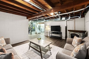 Ein Wohnzimmer mit Kamin, Fernseher und einer Treppe, die in einen oberen Bereich führt.