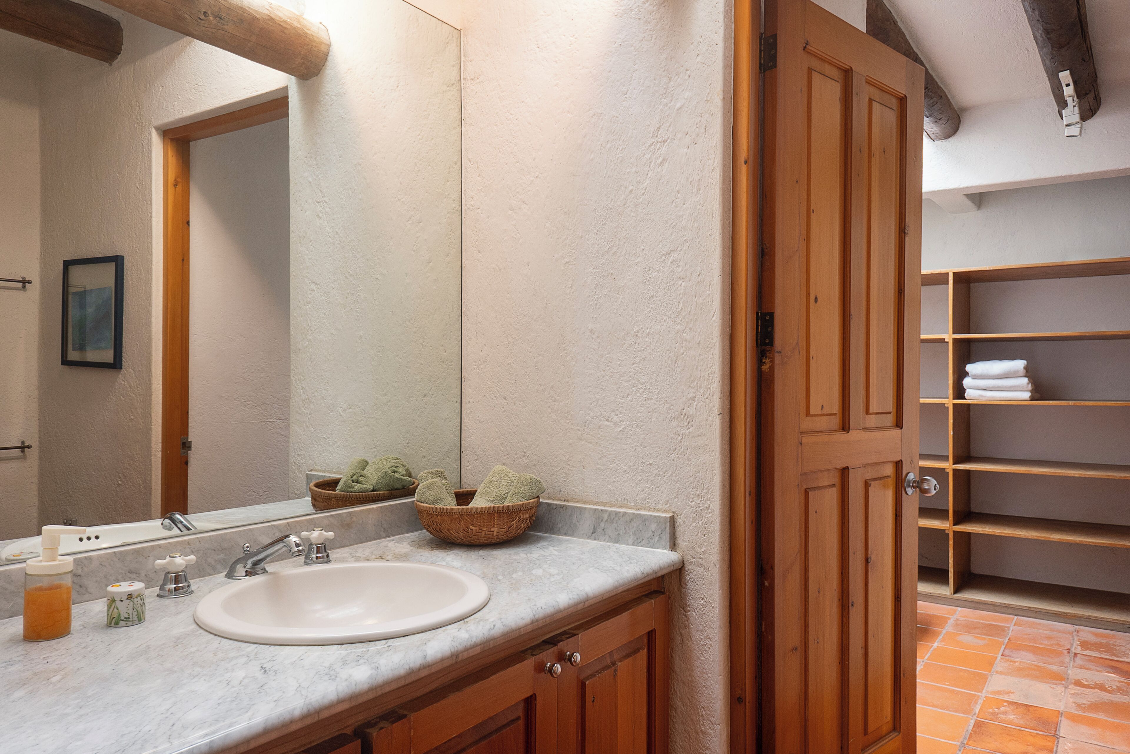 A bathroom with a sink, mirror, wooden cabinets, and a tiled floor.