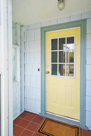 A yellow door with a green frame, white shutters, and a brown doormat. - Charming Seaside Cottage in Victoria's Historic Core (Victoria South)