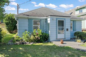 A single-story house with a front porch, a small garden, and a visible chimney. - Charming Seaside Cottage in Victoria's Historic Core (Victoria South)