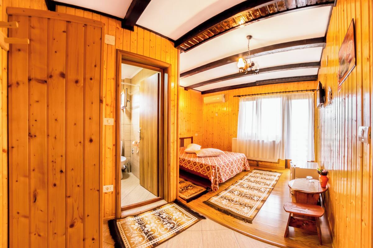 A wooden interior with a bed, a small table, and a bench.