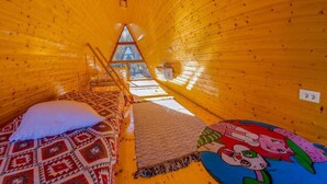 Interior acogedor de una cabaña con una cama, una alfombra y una decoración mural colorida.