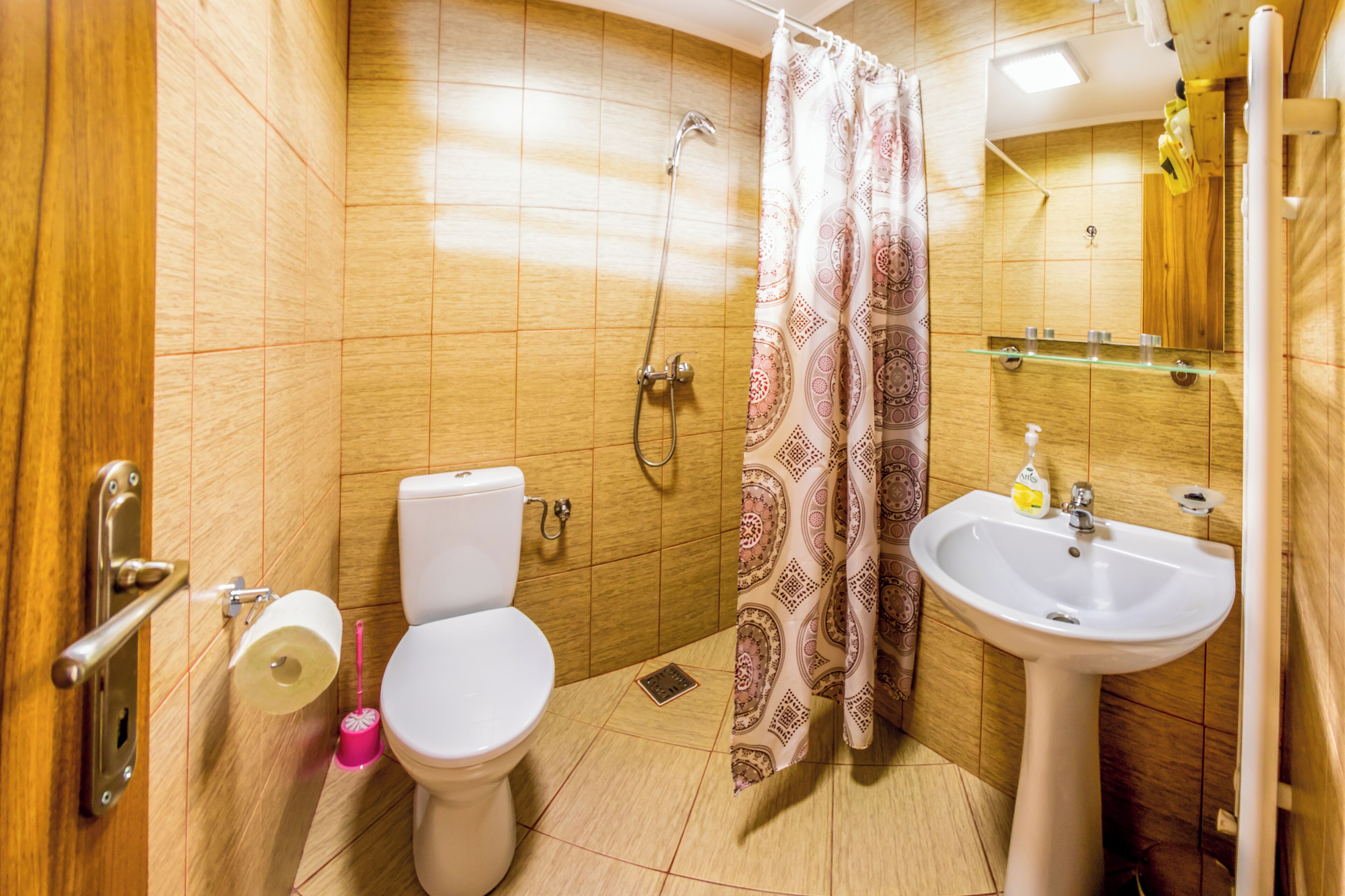 A bathroom with a toilet, shower, sink, and mirror.