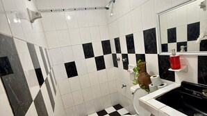 Un baño con piso a cuadros negros y blancos, un inodoro blanco, un lavamanos con recipiente negro y un espejo sobre el lavamanos.