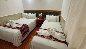 Habitación de hotel con dos camas, cada una con ropa de cama y toallas blancas dispuestas en forma de cisne.