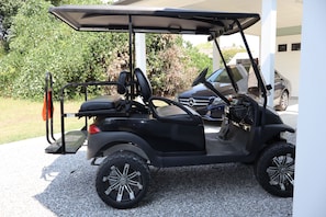 A golf cart parked on a gravel driveway. - Perfect for your Baycation! Comes with 4 person golf cart. (Bay St. Louis)