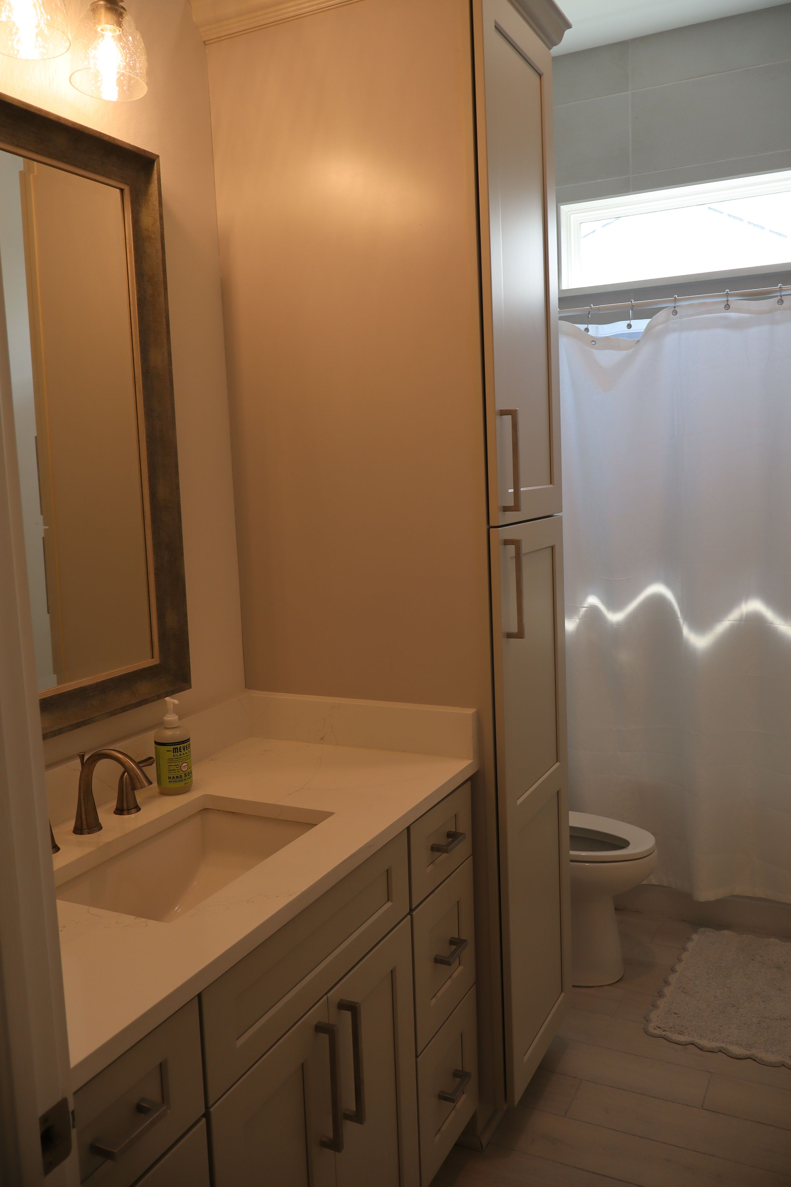 A bathroom with a sink, mirror, cabinet, and toilet.
