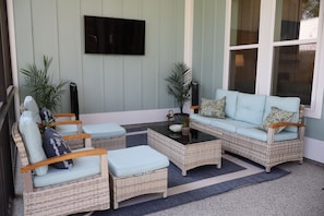 A furnished outdoor seating area with wicker furniture, a flat-screen TV, and potted plants. - Perfect for your Baycation! Comes with 4 person golf cart. (Bay St. Louis)