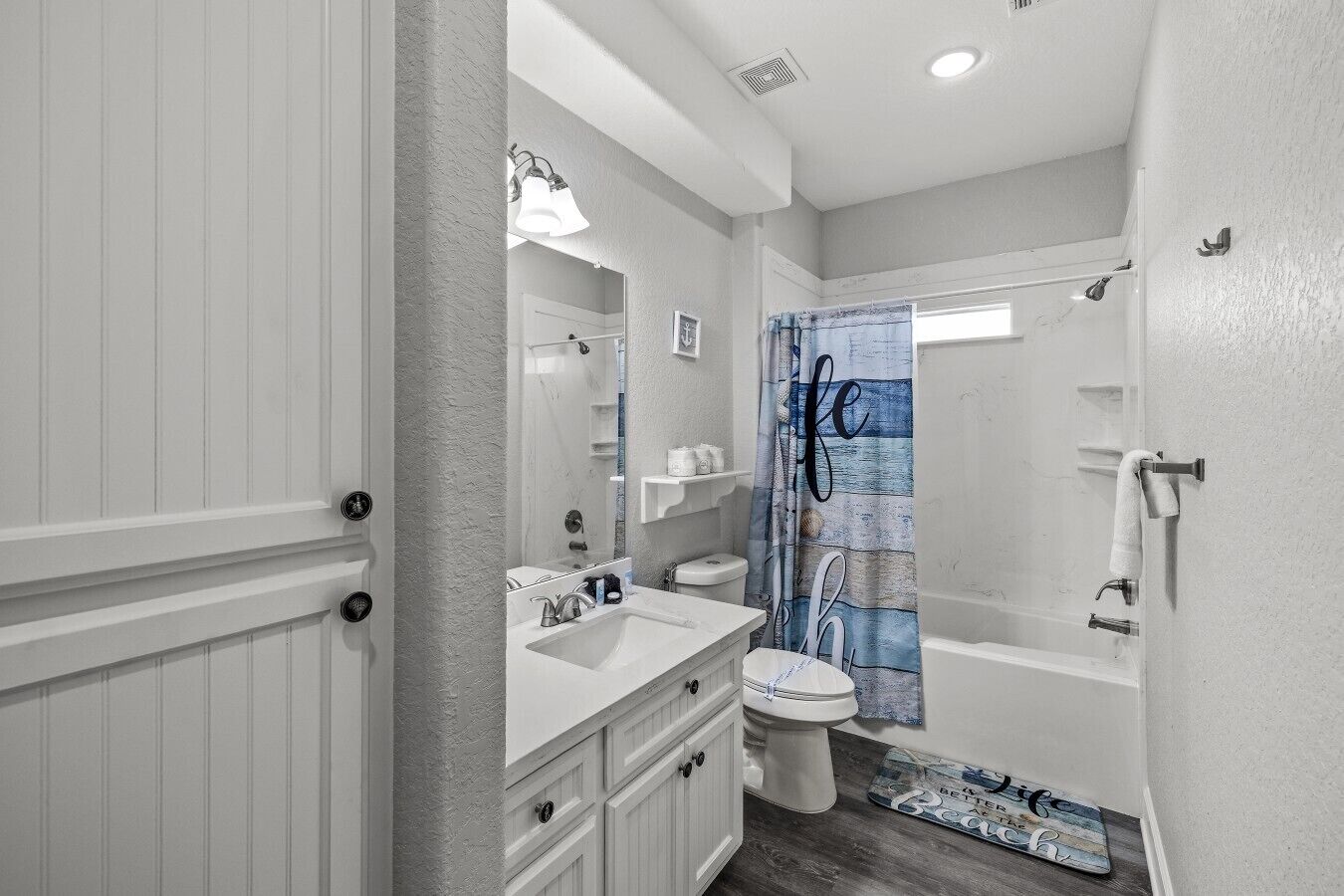 A bathroom with a white vanity, a toilet, and a shower area.