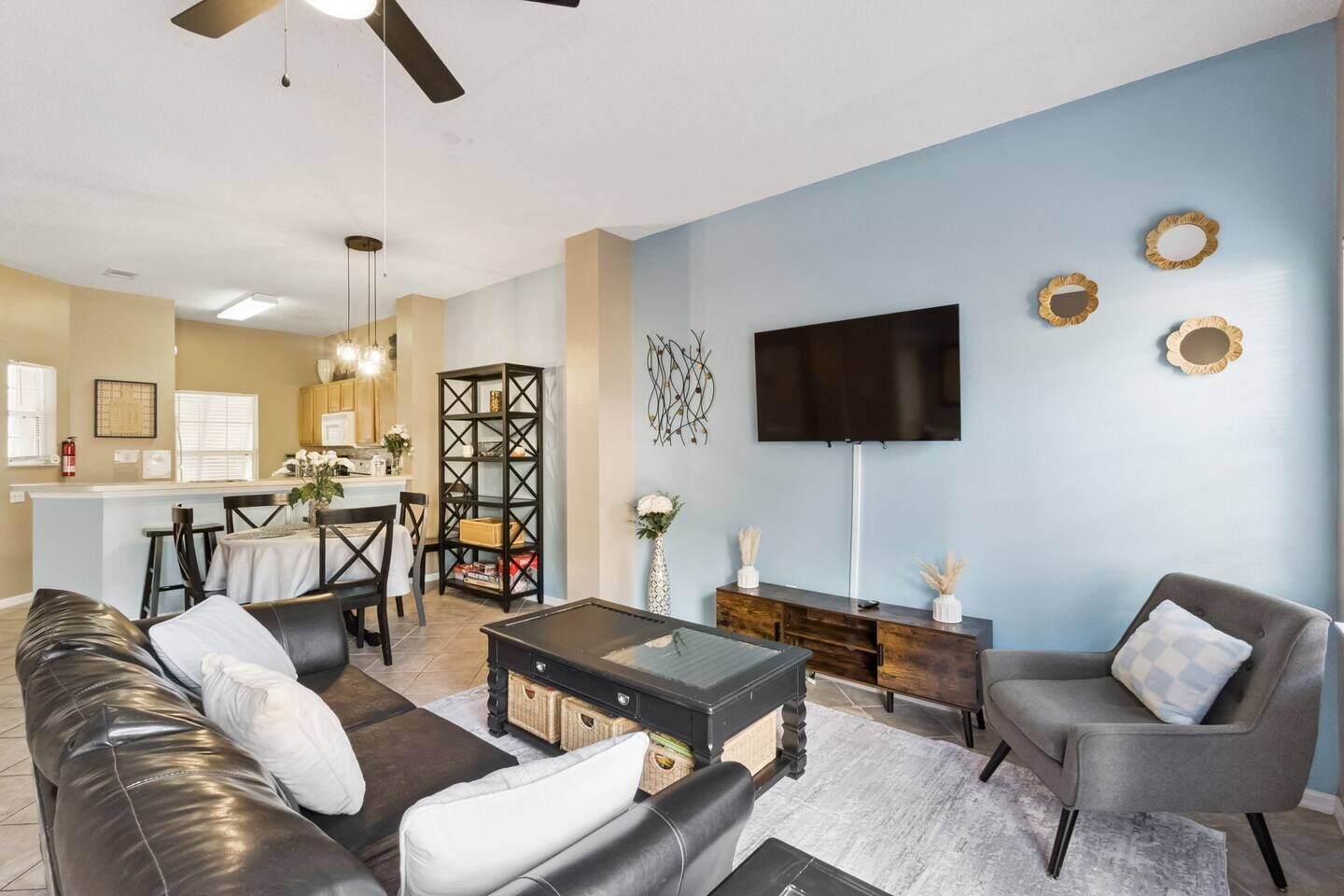 A living room with a sofa, armchairs, a coffee table, and a TV mounted on the wall.