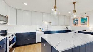 A modern kitchen with white cabinets, a marble island, and pendant lighting. - Rehoboth Beach - 24 Brooklyn Ave Unit E (Rehoboth Beach)