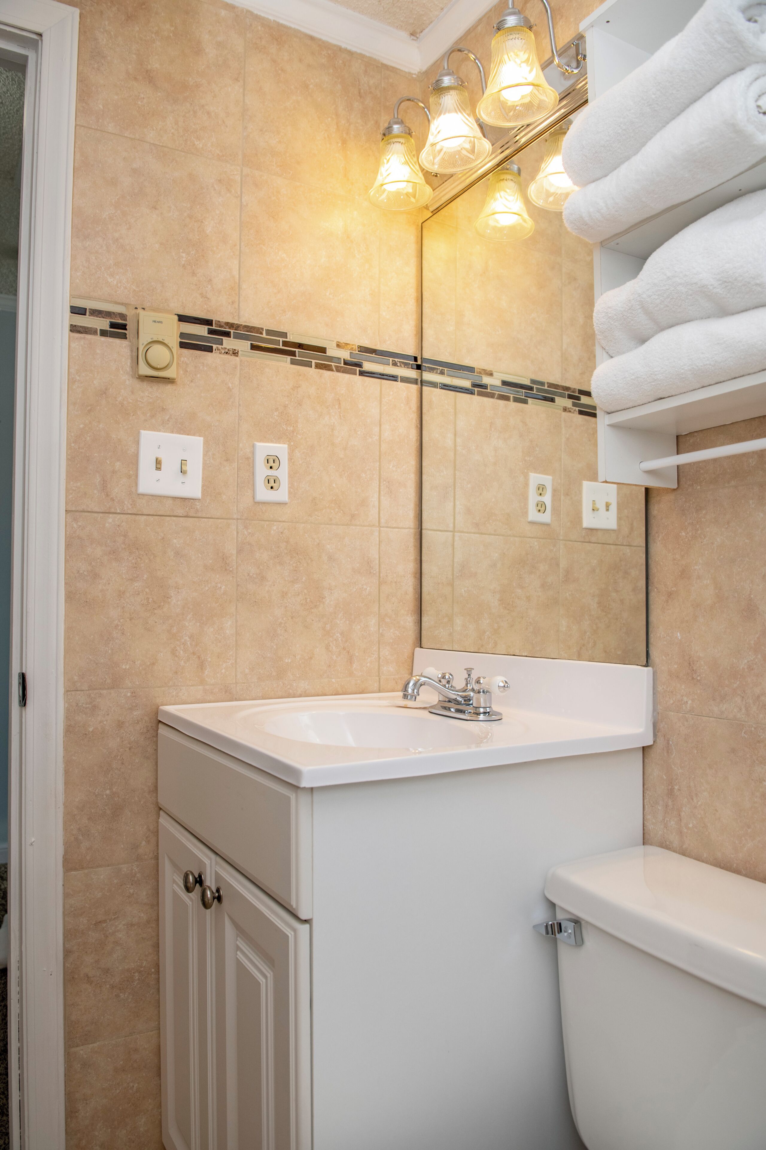 Un bagno con lavandino bianco, un water, uno specchio e un portascopevoli.