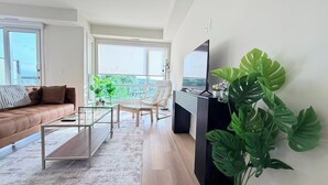 En moderne stue med sofa, sofabord, lænestol og et stort fjernsyn.