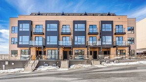 En moderne boligbygning med flere etager, altaner, store vinduer og en murstensfacade.