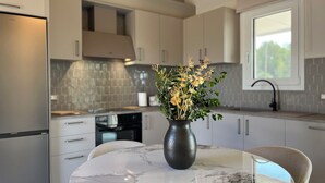 Een moderne keuken met een marmeren tafel, een vaas met bloemen en een raam met uitzicht.