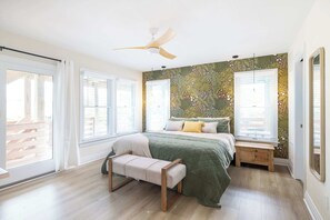 A bedroom with a bed, a bench, a ceiling fan, and a window with blinds. - Duck Resort with Ocean Views, Pool, HotTub, Elevator (Kitty Hawk)