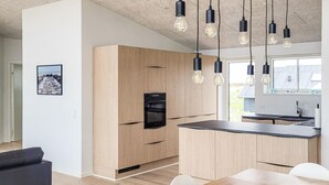 A modern kitchen with wooden cabinets, a built-in oven, and pendant lighting. - Amazing home in Vestervig with WiFi (Vestervig)