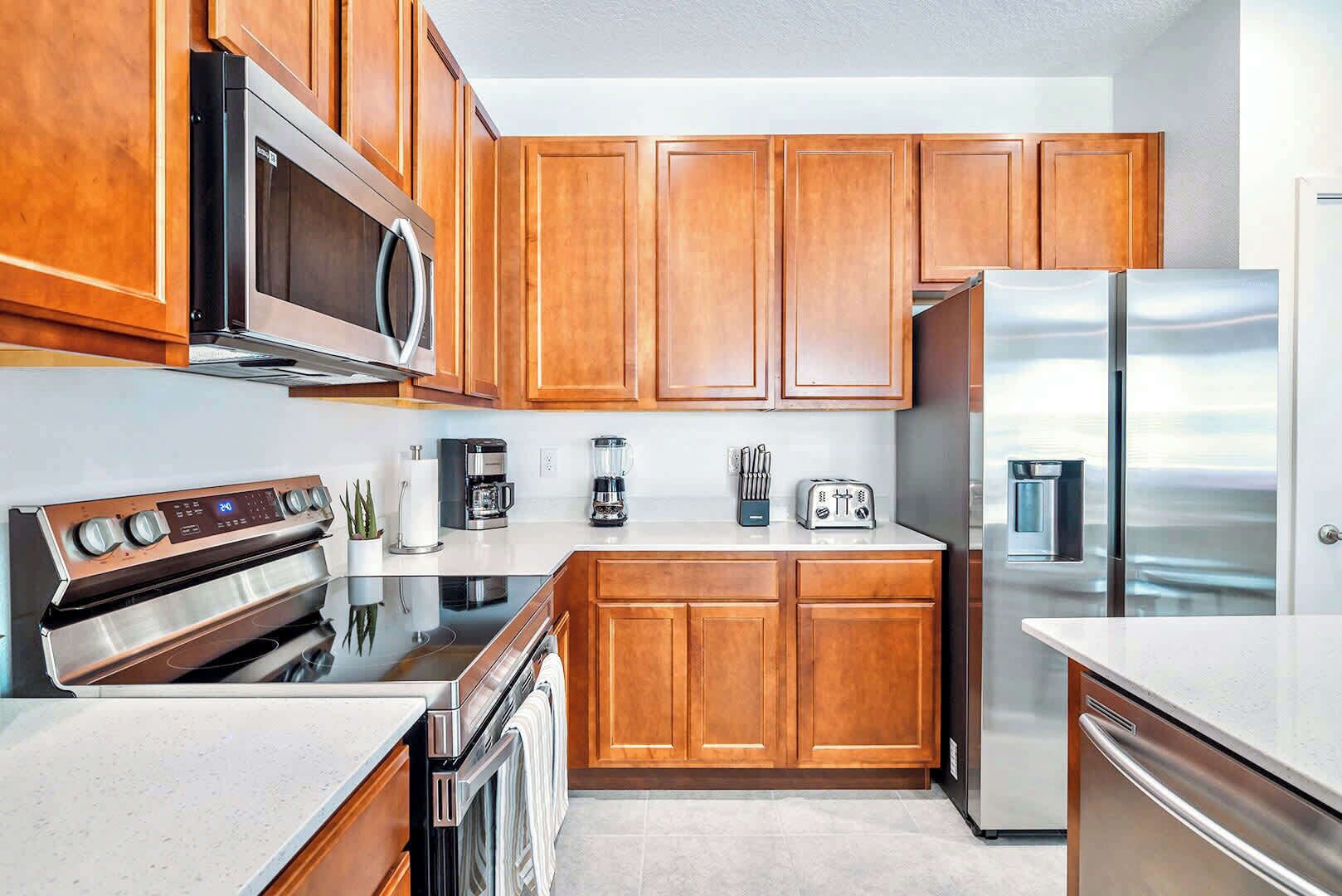 A modern kitchen with wooden cabinets, stainless steel appliances, and a white countertop.