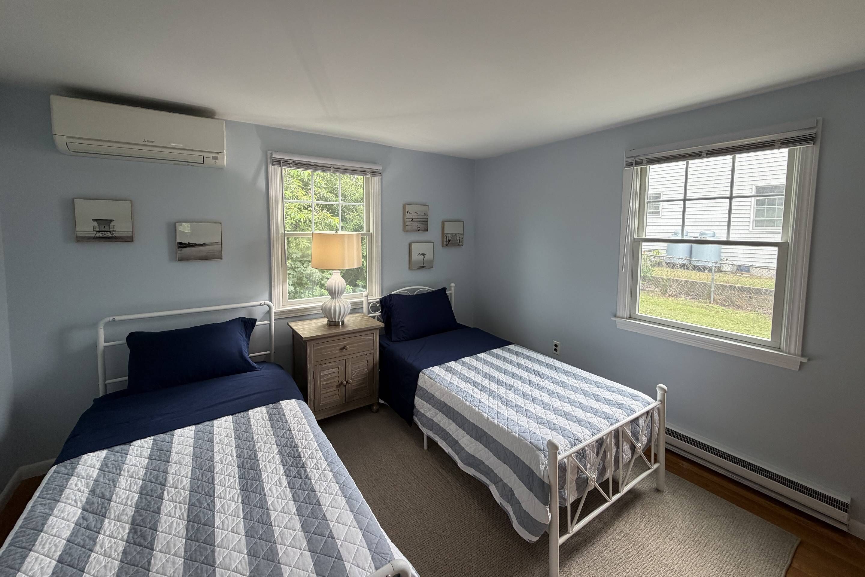 Un dormitorio con dos camas, una ventana y un aire acondicionado.