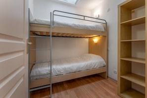 Ein Stockbett mit Dachfenster, ein Nachttisch und ein Holzkoffer.