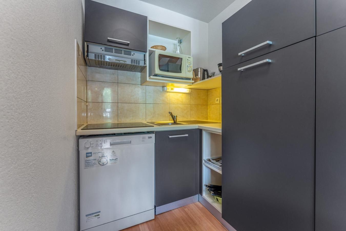 Eine kleine Küche mit Geschirrspüler, Mikrowelle und Kühlschrank.