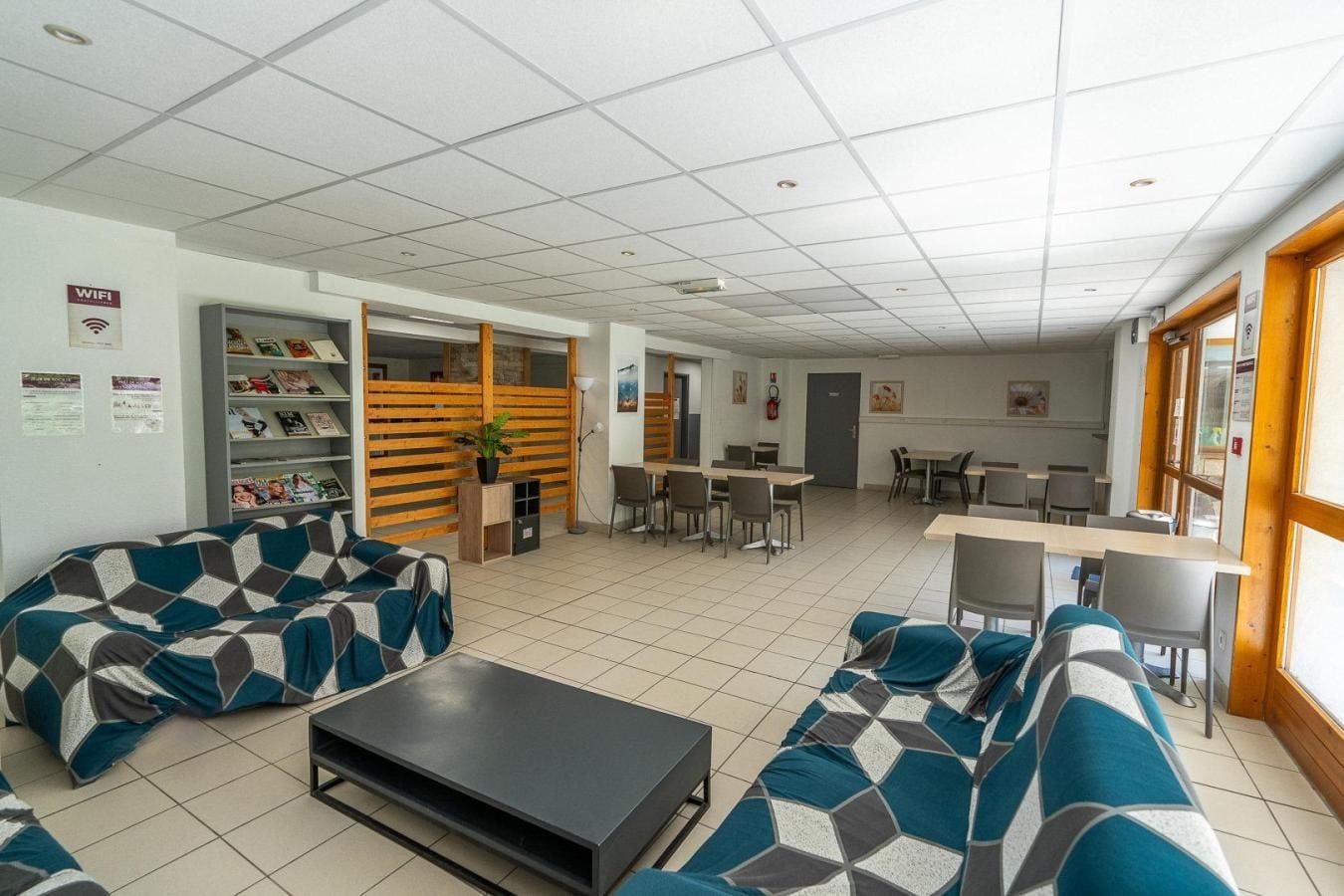 A modern lounge area with sofas, a coffee table, and a dining area with tables and chairs.