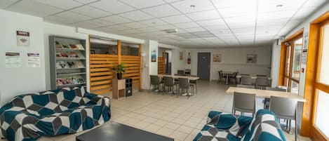 A modern lounge area with sofas, a coffee table, and a dining area with tables and chairs.