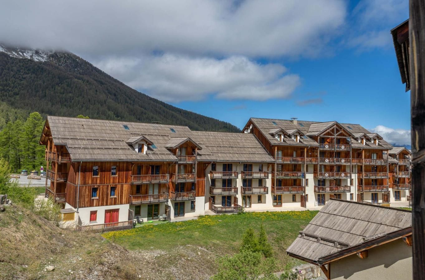 Un edificio de madera de varios pisos con balcones, con montañas al fondo.