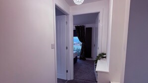 A hallway with a carpeted floor, white walls, and a ceiling light fixture. - 2 bedroom full referbished anex, sleeps 4. Kitchen, Cooker, fridge/freezer. (bradford)