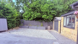 A paved patio area with a gravel section, a wooden fence, and a stone building with windows. - 2 bedroom full referbished anex, sleeps 4. Kitchen, Cooker, fridge/freezer. (bradford)