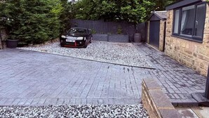 A car parked in a driveway with gravel, a wooden fence, and a building with a window. - 2 bedroom full referbished anex, sleeps 4. Kitchen, Cooker, fridge/freezer. (bradford)