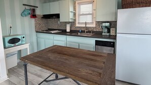 A kitchen with light blue cabinets, a white refrigerator, a wooden table, and a vintage radio.