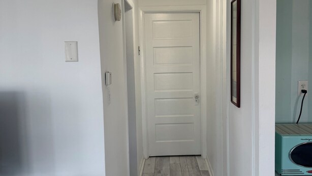 A hallway with a white door, a ceiling light, and a small table.