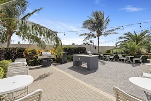 Eine Terrasse im Freien mit Grill, Bar und Sitzgelegenheiten.