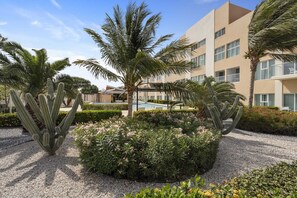Ein Hotel mit Pool, Palmen und Kakteen im Garten.