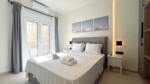 Ett modernt hotellrum med en stor säng, utsikt från balkongen och ett konstverk som hänger på väggen.