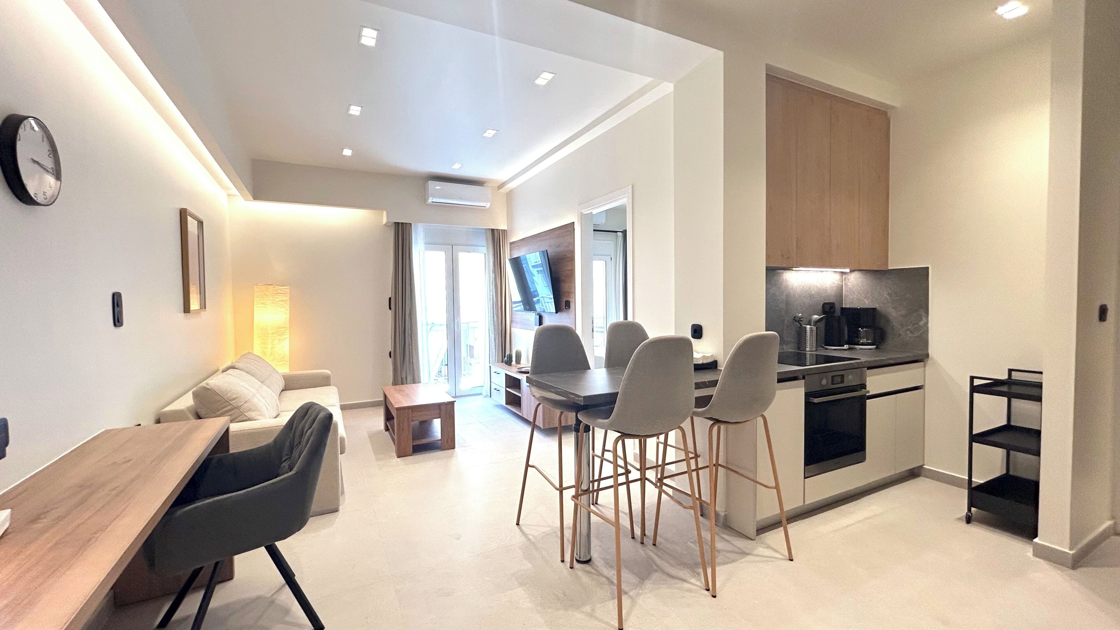 A modern apartment with a dining area, kitchen, and a living space.