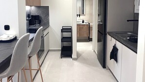 Ett modernt kök med en matplats, utrustat med en bänkskiva, stolar och ett kylskåp.