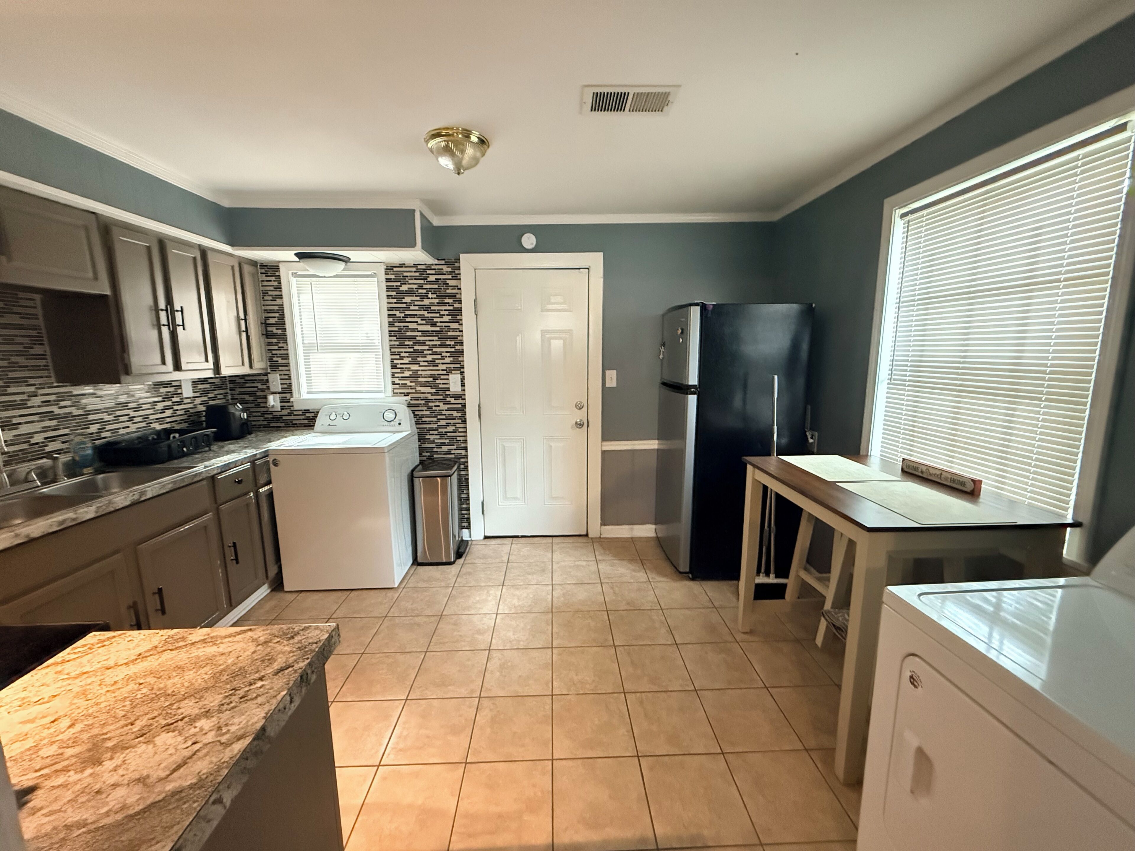 A kitchen with a washing machine, a refrigerator, and a countertop.