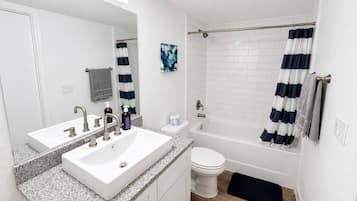 A bathroom with a double sink, toilet, and bathtub.