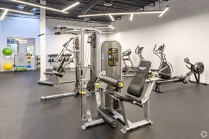 Une salle de sport équipée de divers appareils d’exercice, notamment une machine à presses pour les jambes et un vélo d’appartement.